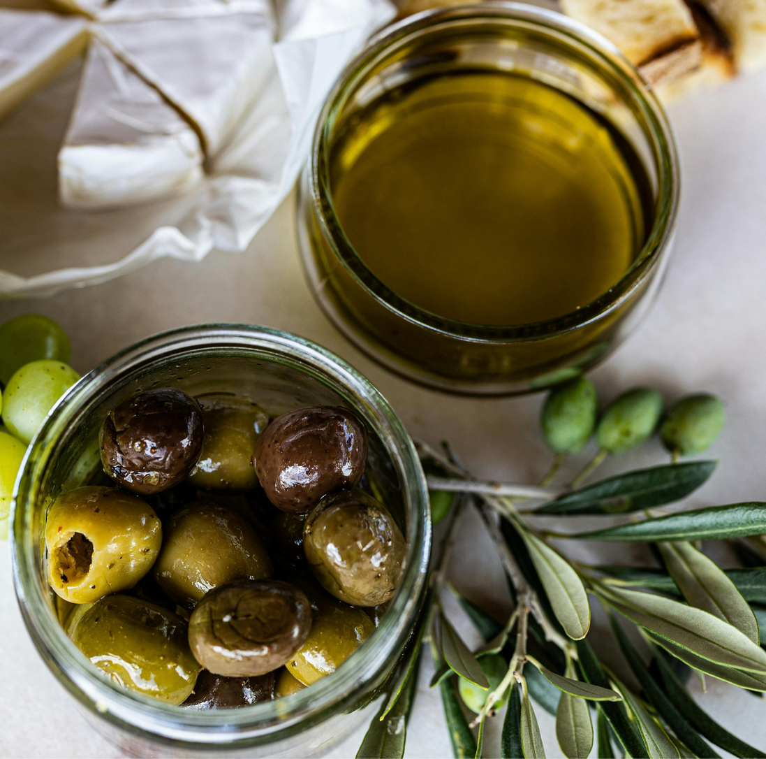 Green and black olives in a bowl with fresh olive branches
