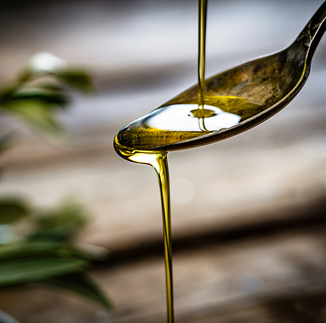 Golden extra virgin olive oil pouring from a spoon